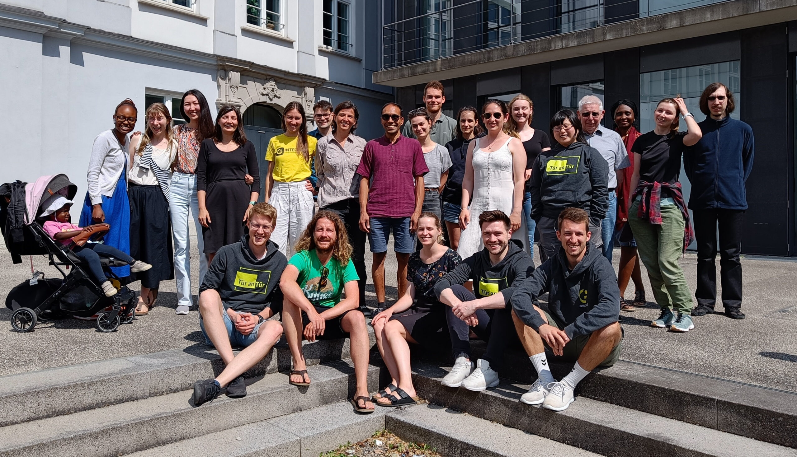 The picture shows the team members at the Integreat conference standing in the sun in front of Augsburg University of Applied Sciences.