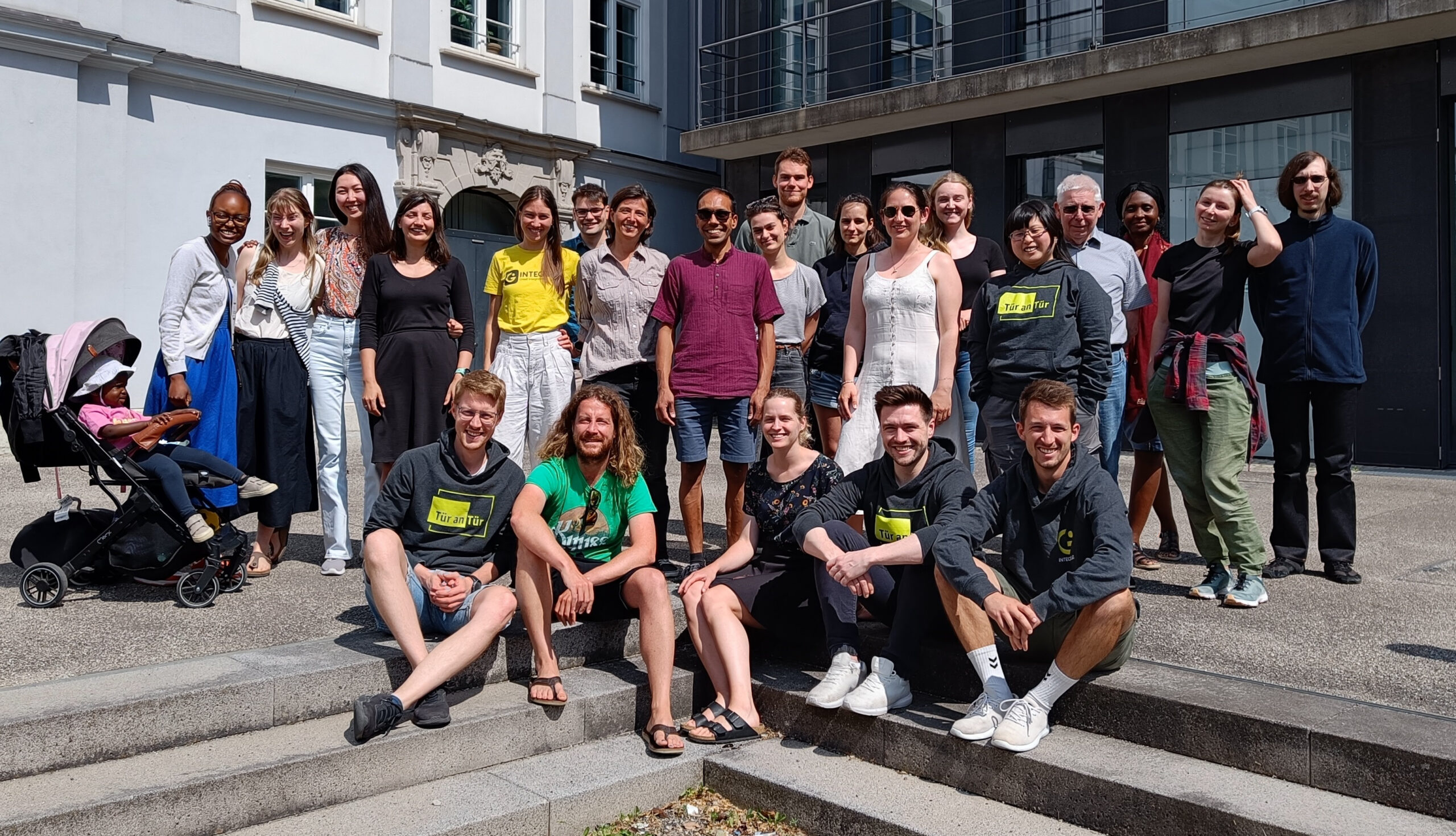 Auf dem Bild sind die Teammitglieder auf der Integreat-Konferenz zu sehen, die vor der Hochschule Augsburg in der Sonne stehen.